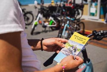 A person holds a brochure titled "Bike Rental & Tours".