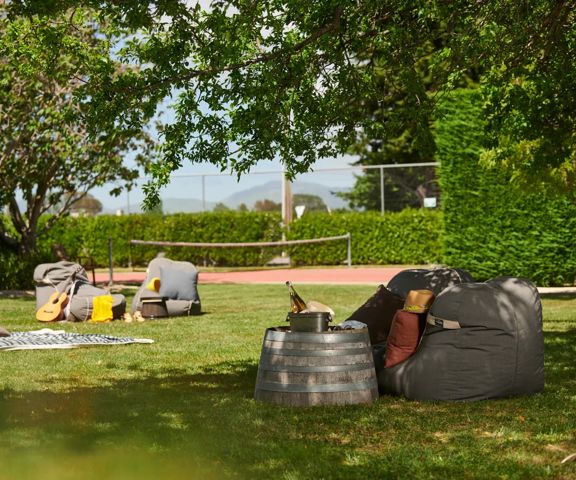 The lawn at Prehua Resort has bean bags and half wine barrels as tables scattered around the lawn.