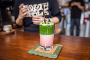 An iced strawberry matcha, made by Pour & twist. The top half od the drink is green and bottom is pink.