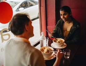 Two friends enjoying bowls of laksa at Rasa Malaysian restaurant.