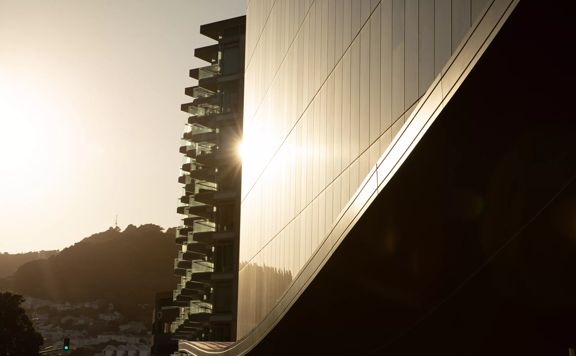 The front facade of Tākina Wellington Convention and Exhibition Centre. The morning sun reflects off the glass windows.