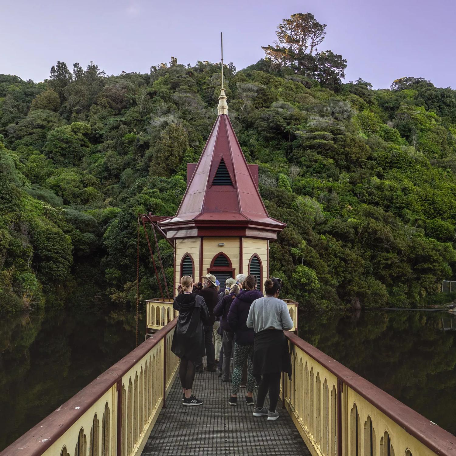 People gather on the bridge to the water tower in the middle of the reservoir at Zealandia. 
