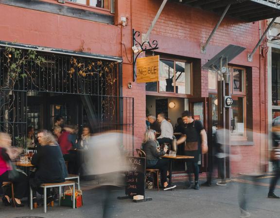 The exterior of a busy wine bar and restaurant with patrons filling both interior and exterior seating.