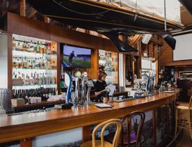 A server behind the bar cleaning glasses at Dockside on Queens Wharf.