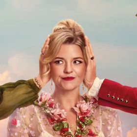 An opera performer with other people's hands from out of frame over their ears on a blue sky background.