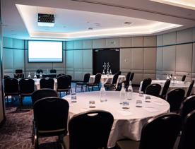 A conference room set up with round tables, waters and black chairs at the InterContinental Hotel in Wellington Central.