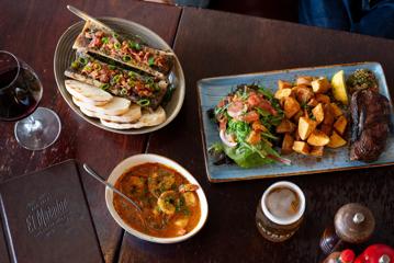 Three dishes on a table with a glass of red wine and a pint of beer at El Matador.