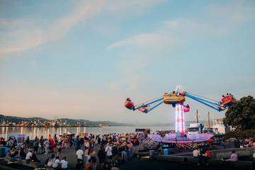 A colourful carnival ride on the waterfront during a festival.