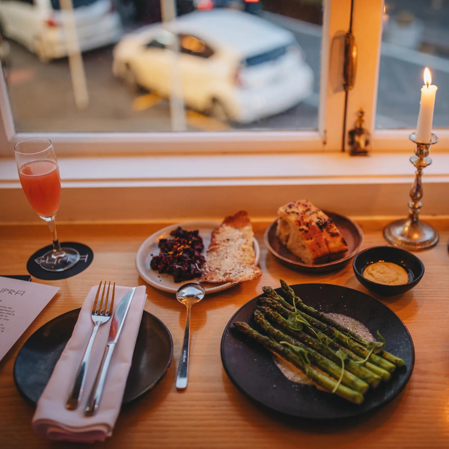 Plates of food and drinks at Supra. The camera angle is looking down from above and the road below is seen through the window.