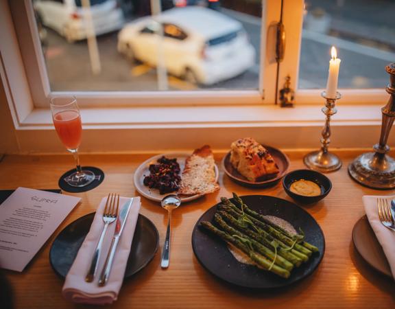 Plates of food and drinks at Supra. The camera angle is looking down from above and the road below is seen through the window.