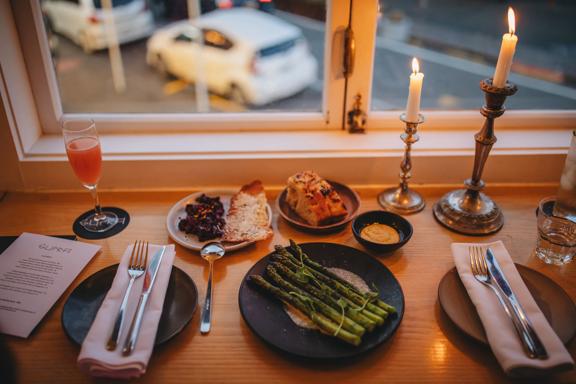 Plates of food and drinks at Supra. The camera angle is looking down from above and the road below is seen through the window.