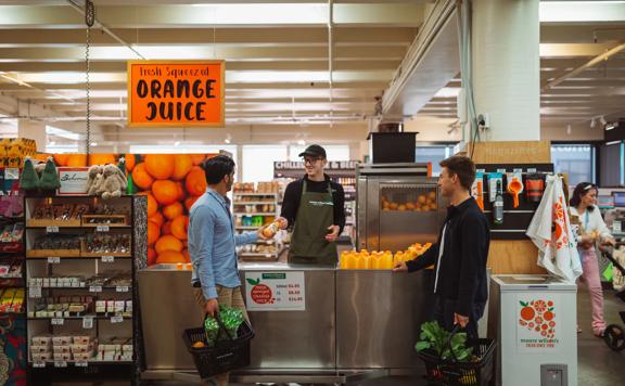 Two shoppers pick up some freshly squeezed orange juice at Moore Wilson's.