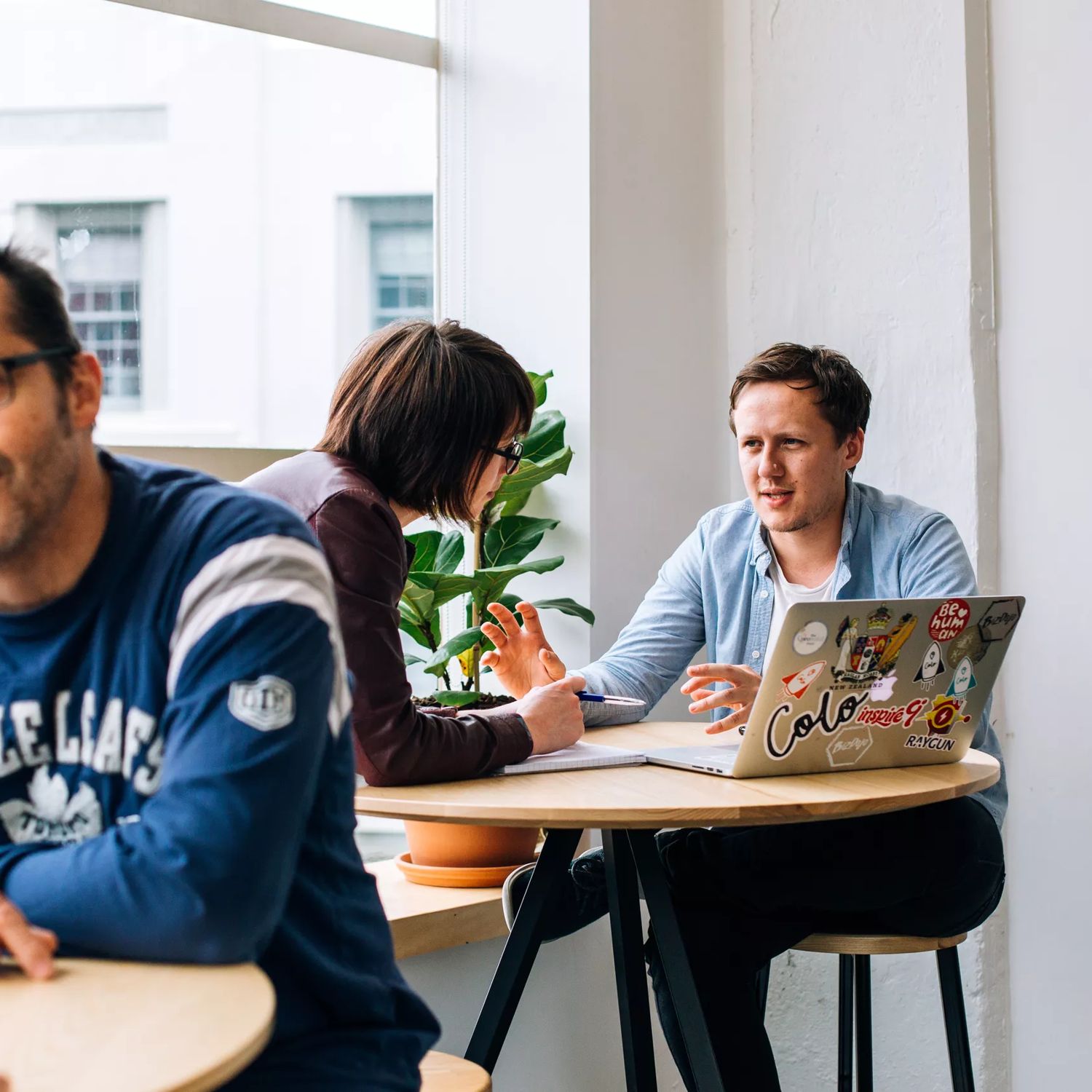 Looking over at two colleagues working at a small high table at BizDojo, Wellington.