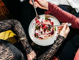 Looking down at a table of food inside Hippo, QT Wellington. Customers use a knife and fork to grab food.