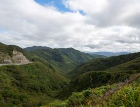 The screen location of Remutaka Summit, wit views of surrounding peaks, lush green bush and steep roads cut into the sides of the mountains.