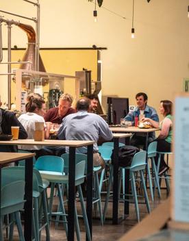 People enjoy drinks and food a the high tables inside Heyday Beer Co.