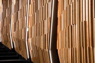 A wall with verticle wood panels and verticle strips of LED lights.