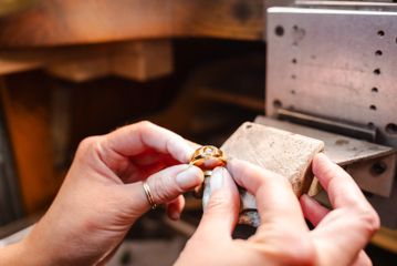 Hands hold a Floeting diamond ring from The Village Goldsmith.