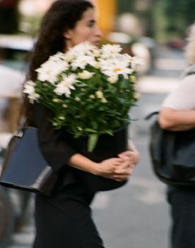 Person carrying a bucket of white flowers.