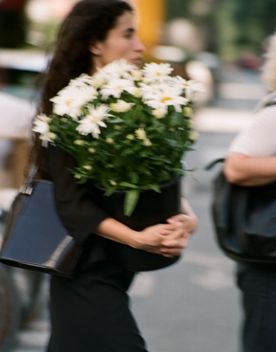 Person carrying a bucket of white flowers.
