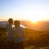 Two people stand arm in arm looking at a picturesque sunset from Rangituhi/Colonial Knob Walkway.