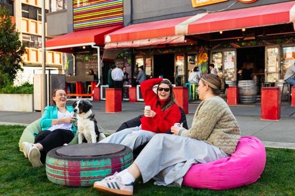 Three friends and a dog sit on beanbags outside of Rogue & Vagabond in Te Aro, Wellington. 