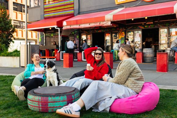 Three friends and a dog sit on beanbags outside of Rogue & Vagabond in Te Aro, Wellington.