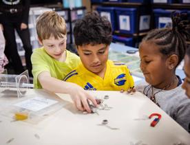 3 young children play with magnets and paperclips at House of Science.