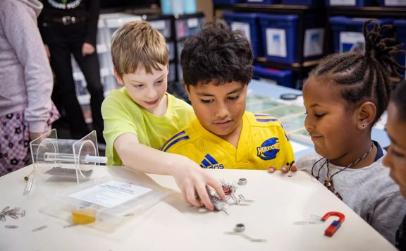 3 young children play with magnets and paperclips at House of Science.