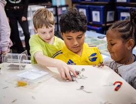 3 young children play with magnets and paperclips at House of Science.
