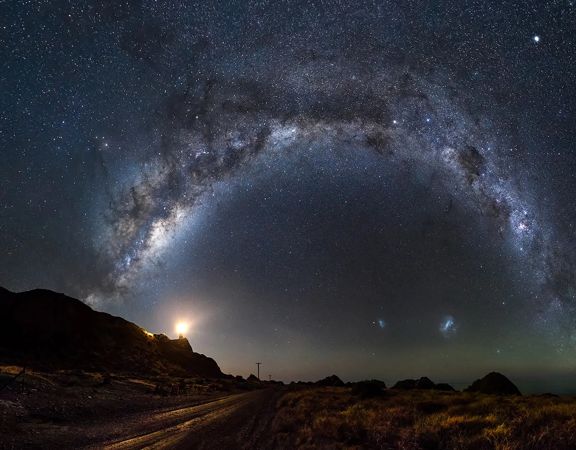A panorama of the Milky Way high in the sky, stretching from east to west. Shot at a Wairarapa Dark Sky reserve location at Cape Palliser on the bottom of the North Island of New Zealand.