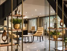 The lobby inside Sofitel Wellington. A gold accent colour is spread throughout the chairs, shelves, pot plants, and curtains.