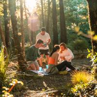 Group of friends taking a break from walking and laying out a small picnic in the middle of a forest at Butterfly Creek.