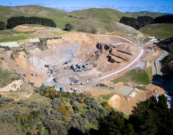 An aerial view of the Willowbank Quarry with work trucks and heavy machinery under a sunny blue sky. 