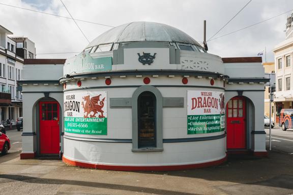 The exterior of The Welsh Dragon Bar, a pub set inside a former public toilet on Cambridge Terrace in Wellington. The building has a circular dome with two red doors on either side. 