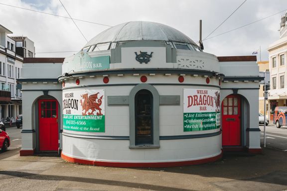 The exterior of The Welsh Dragon Bar, a pub set inside a former public toilet on Cambridge Terrace in Wellington. The building has a circular dome with two red doors on either side.