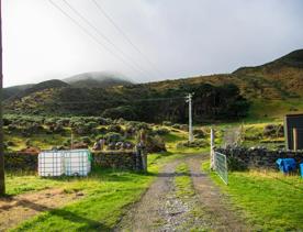 The screen location of Ōrongorongo Station, with many buildings, old and new, as well as views of the ocean and mountains.