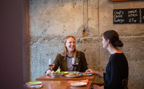 2 customers enjoy their meals and talk over food at Graze Wine Bar.