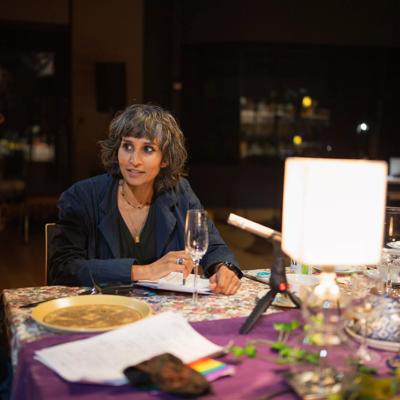 Raqi Syed seated at a table talking with another person.