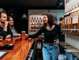 A bartender sets a freshly-poured pint down on the counter at Garage Project, Aro Taproom.