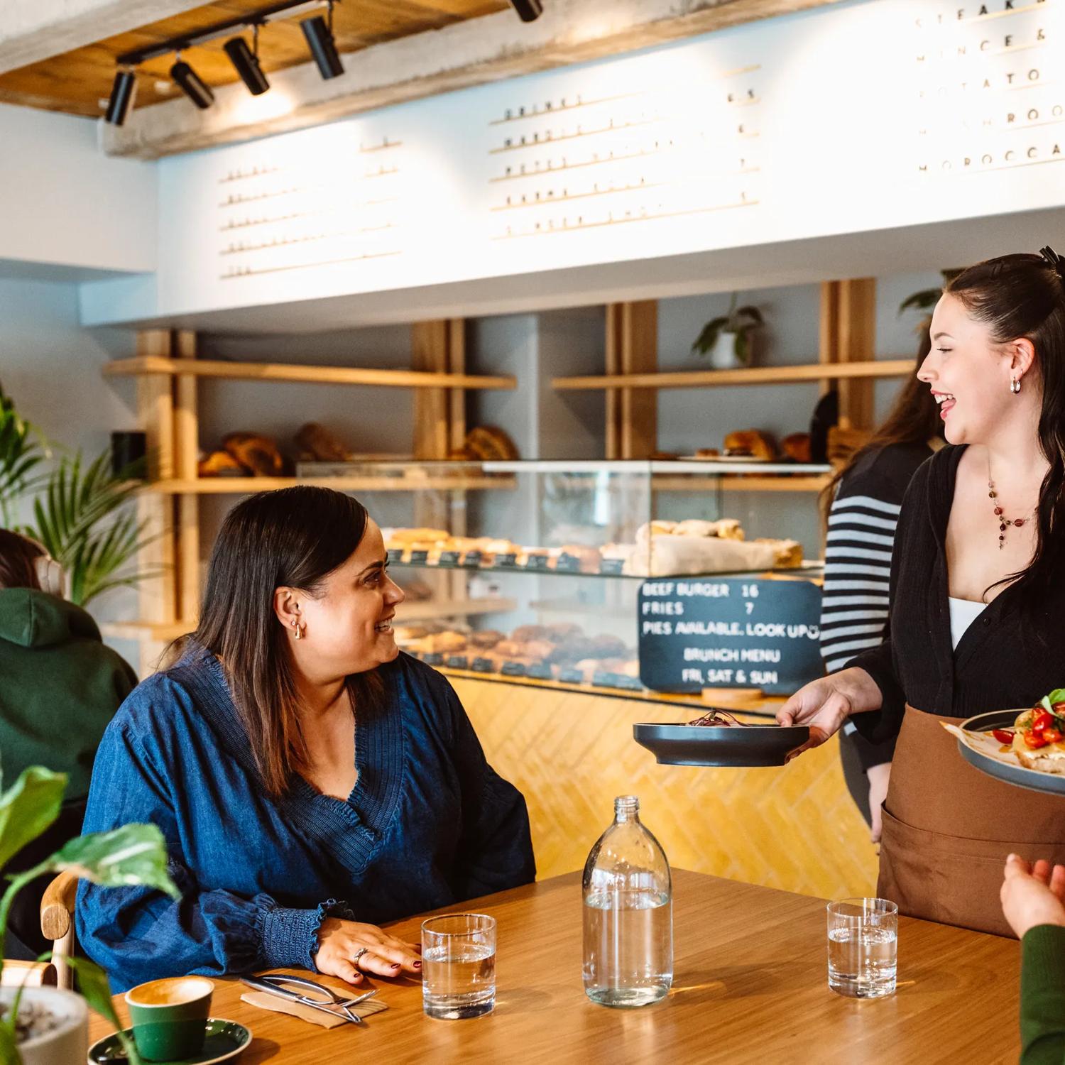 A server delivers two brunch dishes to a table of two.