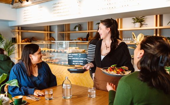 A server delivers two brunch dishes to a table of two.