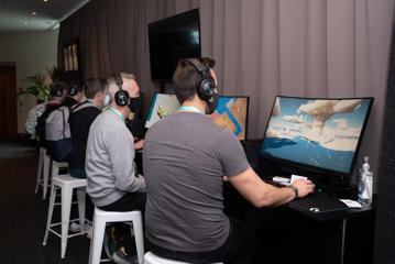 Five people are sitting at a table, testing out newly developed computer games at the 2022 NZGDC Game Developers Conference at Te Papa.