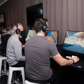 Five people are sitting at a table, testing out newly developed computer games at the 2022 NZGDC Game Developers Conference at Te Papa.