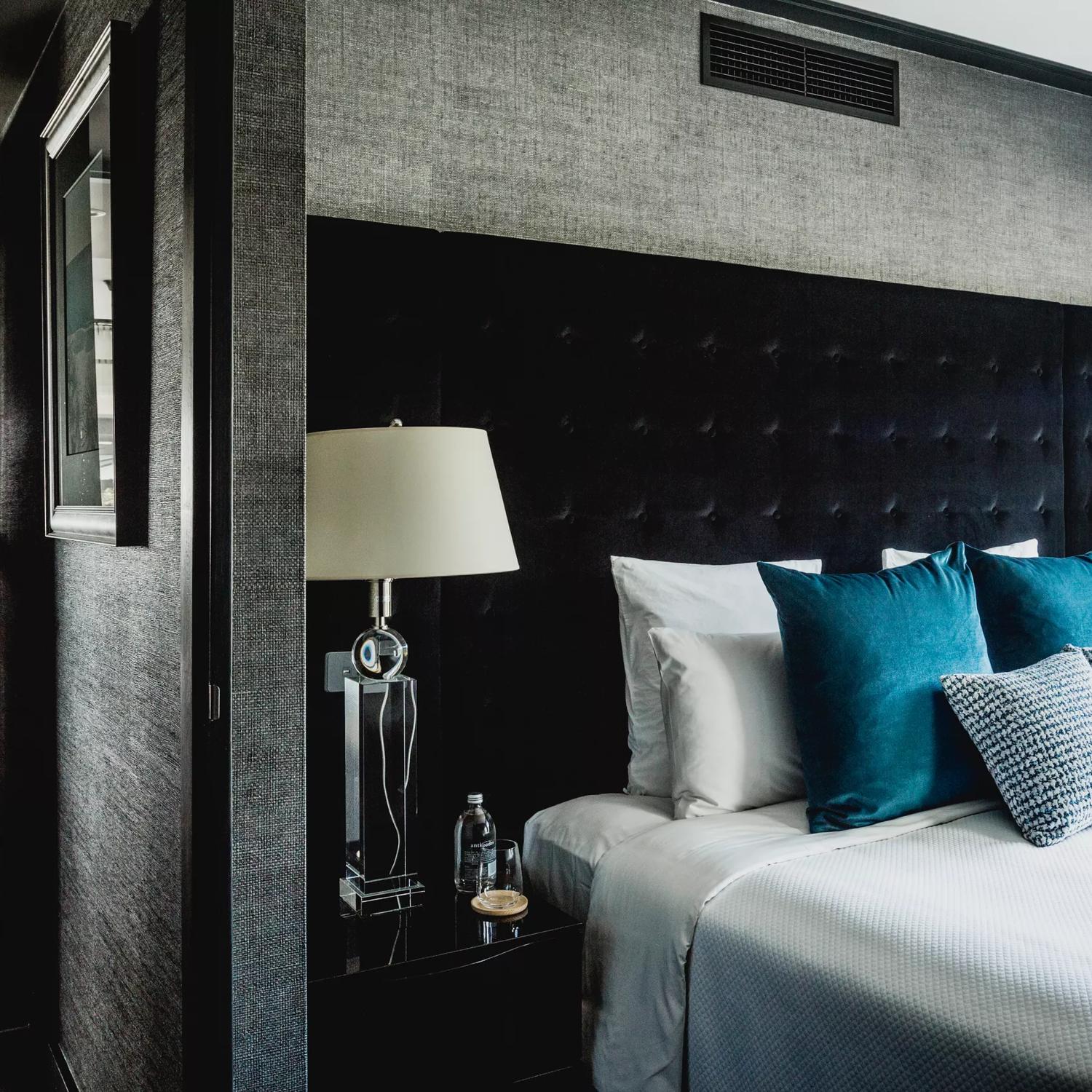 Bolton Hotel Residence Suite with a bed in the foreground and down the hallway, a dining table.