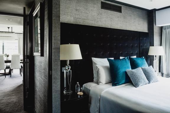 Bolton Hotel Residence Suite with a bed in the foreground and down the hallway, a dining table.