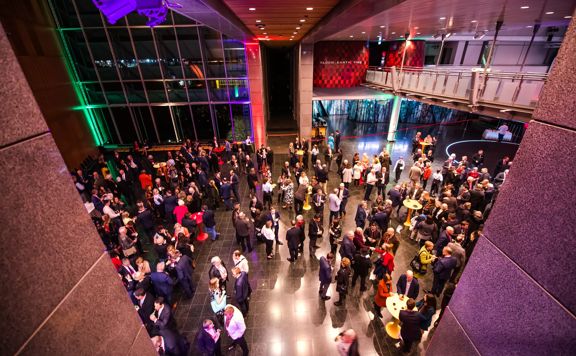 The foyer room at the Museum of New Zealand Te Papa Tongarewa during a event. The space is full of people in semi-formal wear.