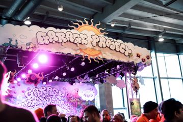 Crowd of people standing in front of the Garage Project station at Beervana, with signage and lettering made to look like clouds.