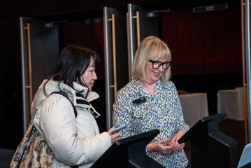 A Tākina host helps a delegate sign in on iPads at the New Zealand International Education Conference.