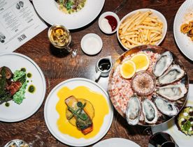 Looking down at a table of food inside Hippo, QT Wellington. The dishes include oysters and salmon.